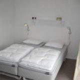 Ein Doppelbett mit Nachtisch und einem Regal über dem Bett.