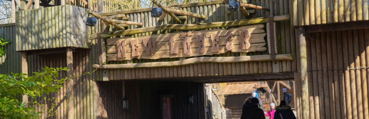 Das Schild NEW LÜBECK an der Brücke. Gäste gehen unter der Brücke lang.
