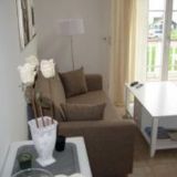 Couch mit zwei Sesseln und einen Couchtisch. Im Hintergrund eine Fensterfront.