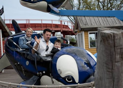 Die Attraktion Flying Orca mit einem Orca in dem Gäste sitzen, der von links ins Bild kommt.