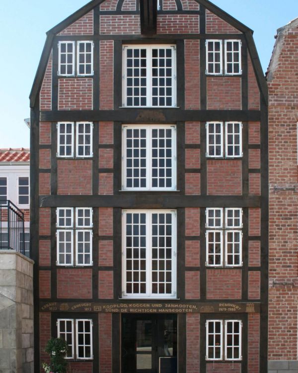 Ein Speicherhaus der Reimerstwiete aus Hamburg im Fachwerkstil, weiße Fenster und einem Giebelkran.