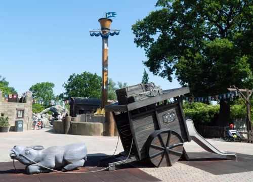 Ein liegender Esel. Dahinter ein Karren mit einer Rutsche. Im Hintergrund Awildas Welt.