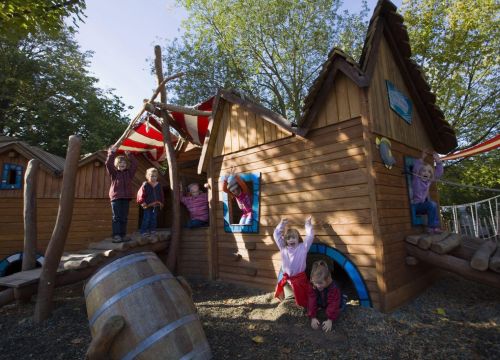 Aus dem Häuschen des Niedrigseilgartens gucken Kinder raus. Sie freuen sich.