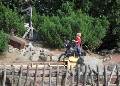 Ein Junge schießt auf dem Pferd auf die interaktiven Ziele der Attraktion Pony Post.