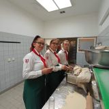 Zwei junge Frauen und ein junger Mann in HANSA-PARK Arbeitskleidung bereiten Teigwaren zu.