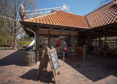 Beim Kiosk an der Schiffschaukel stehen Gäste und bekommen von der Servicekraft ihre Bestellung.