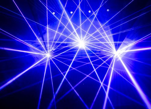 Im Nebel der Lasershow zeigen blau Laserstrahlen in die Luft. Von drei Punkten aus.