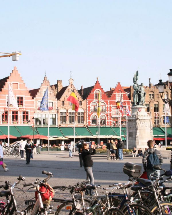 Der Markt von Brügge. Im Hintergrund sind viele Fassaden. Menschen sind auf dem Markt.