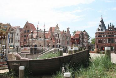 Ein Ruderboot liegt im Vordergrund. Im Hintergrund sind die Arcaden aus Brügge und Hamburg.