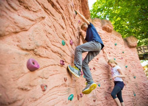 Ein Junge und ein Mädchen sind an der Kletterwand. Der Junge ist im Vordergrund.