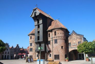 Das Krantor von Danzig von vorne. Davor sind Schilder und ein Schild für eine Raucherinsel.