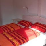 Ein Doppelbett mit Nachtisch und rot gemustertem Bettzeug.