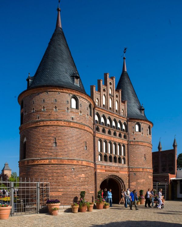 Das Holstentor aus Lübeck seitlich. Besucher kommen aus dem Bogen des Holstentors raus.