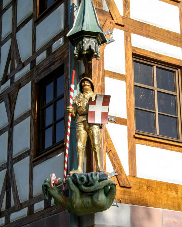 Das Pilatushaus aus Nürnberg. Eine Figur mit einer Stechlanze und einem Schild mit einem Dach.