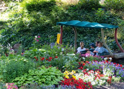 Ein Boot mit Gästen fährt durch die bunte Blumenpracht der Attraktion Blumenmeer-Bootsfahrt.