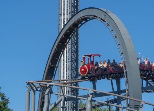 Der Zug des Royal Scotsman fährt unter dem Looping der Bahn Nessi durch. Die Gäste heben die Hände.