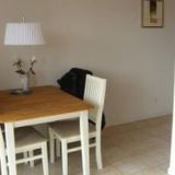 Ein Tisch mit vier Stühlen. Eine Lampe und eine Vase stehen auf dem Tisch.