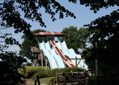 Die Attraktion Barracuda Slide hat vier blaue Rutschen. Ein Laufband transportiert die Boote hoch.