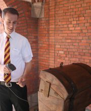 Ein junger Mann des HANSA-PARK mit einem Handscanner am Einlass scannt etwas ein. Er lächelt.