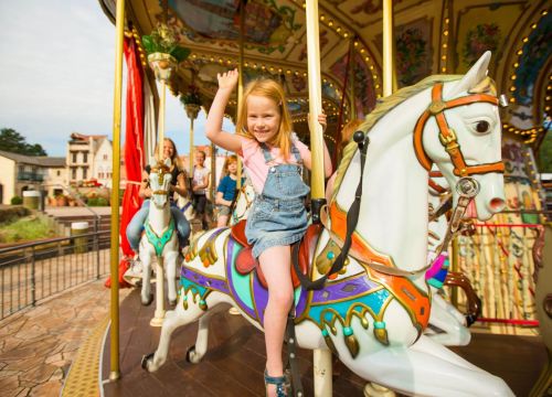 Mädchen auf einem Pferd auf den HANSE-Karussell. Das Pferd hat ein Zaumzeug und einen bunten Sattel.