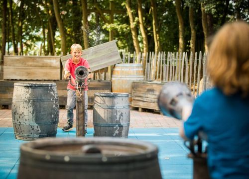 Zwei Jungs stehen sich gegenüber und wollen sich gegenseitig auf dem Wasserspielplatz nass machen.