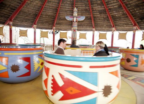 In den Tassen der Attraktion Pow Wow sitzen Gäste. Die Tassen drehen sich.