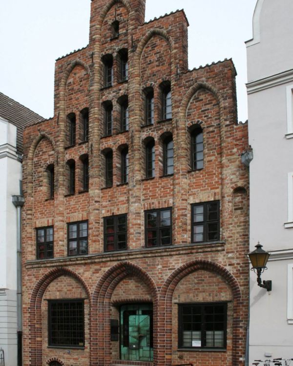 Das Originalgebäude des Hausbaumhaus aus Rostock. Es hat viele Fenster und eine Treppe für zur Tür.
