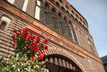 Das Holstentor des HANSA-PARKs von unten fotografiert. Davor ein Topf mit roten und weißen Blumen.