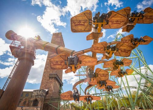 Die Gondeln der Attraktion KÄRNAPULTEN in Bewegung. Im Hintergrund die Achterbahn Schwur des KÄRNAN.