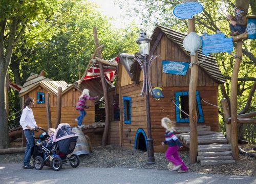 Die Kletterhäuser des Niedrigseilgartens. Kinder rennen, klettern und toben. Eine Mutter beobachtet.