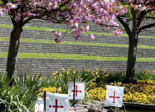 Die Fernlenkschiffe auf dem Wasser. Im Hintergrund Kirschbäume in Blüte und Blumen in den Beeten.