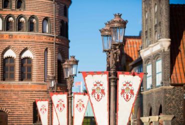 Die Laternen tragen Wimpel mit dem HANSA-PARK-Wappen. Im Hintergrund hanseatische Arkaden.