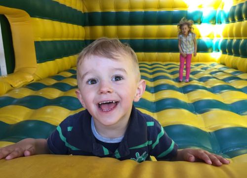 Kinder im Bereich Hüpfen des Ball- und Hüpfhaus. Ein Mädchen hüpft und ein Junge guckt aus dem Bild.