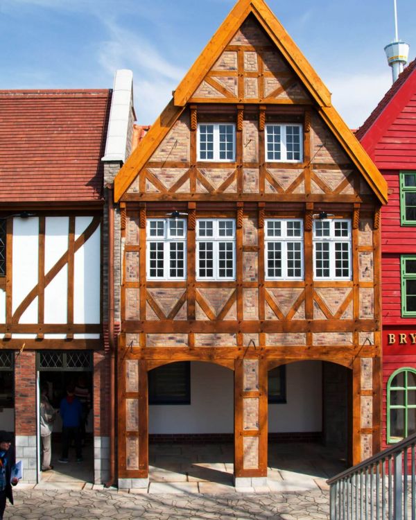 Blick auf die Arkaden des Vorplatzes. Das Gebäude ist im Fachwerkstil mit weißen Fenstern.