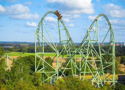 Die Schiene des Schwur des KÄRNAN erhebt sich aus den Bäumen. Im Hintergrund sind Felder.