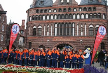 Ganz viele Mitglieder der Jugendfeuerwehr vor der Blumenuhr des HANSA-PARK. Hintergrund: Holstentor.