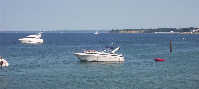 Motorboote in der Ostsee. Sie liegen vor Anker. Im Hintergrund sieht man eine Steilküste.