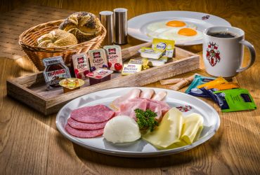 Auf einem Tisch sind Brötchen, süßer oder herzhafter Aufschnitt. Ein Kaffee und auch Teebeutel.