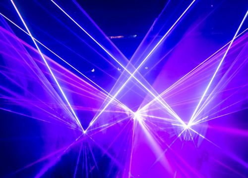 Im Nebel der Lasershow zeigen rosa und weiße Laserstrahlen von drei Punkten in die Luft.