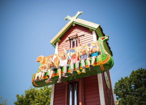 In den Sitzen von Elins Luftreise sitzen Kinder. Sie heben die Arme. Sie sind ganz oben.