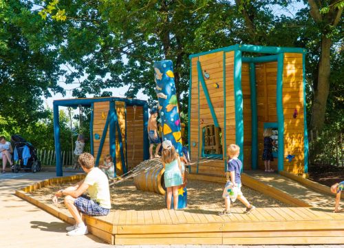 Ganz viele Kinder auf dem Inklusionspielplatz Patio del Mar. Ein Mann sitzt und wartet.