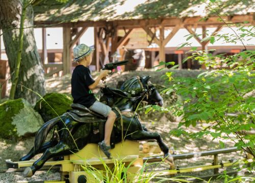 Ein Junge reitet mit einem schwarzen Plastikpferd über die Bahn der Attraktion Pony-Post.