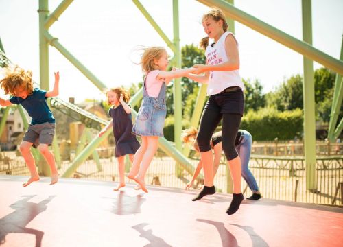 Kinder sind auf dem Hüpfberg. Zwei Mädchen halten sich fest. Dahinter hüpfen auch Kinder.