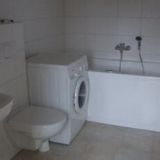 Ein Badezimmer mit Waschmaschine, Badewanne, Toilette und Waschbecken.