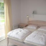 Ein Doppelbett mit Nachtisch und einem Regal über dem Bett.