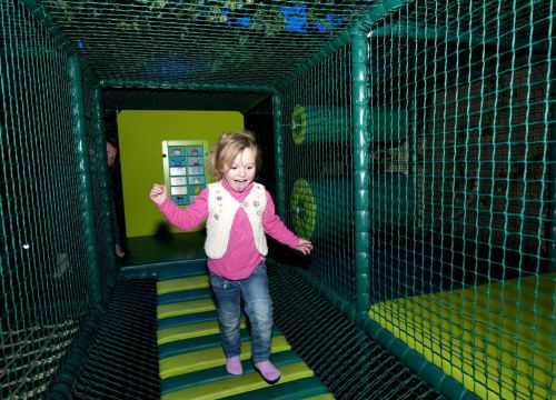 Ein Mädchen ist auf dem Wackelboden im Tahiti Trail. Sie freut sich und konzentriert sich dabei.