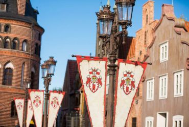 Die Laternen tragen Wimpel mit dem HANSA-PARK-Wappen. Im Hintergrund hanseatische Arkaden.