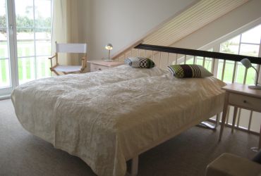 Doppelbeet auf einer eigenen Etage. Das Bett ist mit einer Tagesdecke bedeckt.