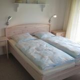 Ein Doppelbett mit Nachtisch und einem Regal über dem Bett.