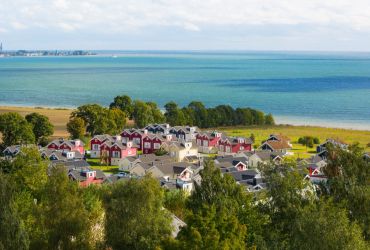 Aufnahme von oben. Die Häuser des Resorts umringt von Bäumen. Dahinter die Ostsee.